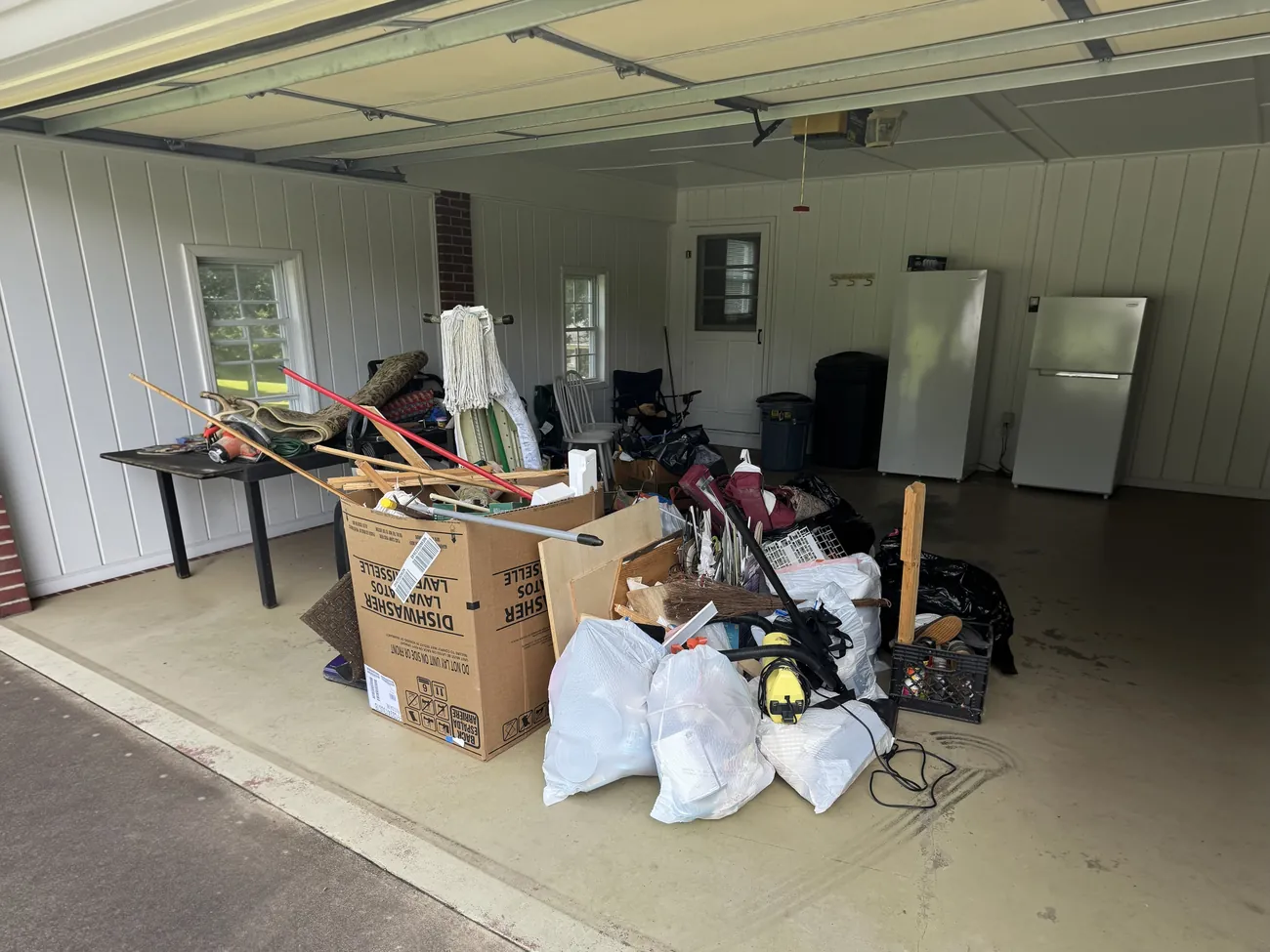 A garage filled with boxes, bags, tools and household items before a cleanout