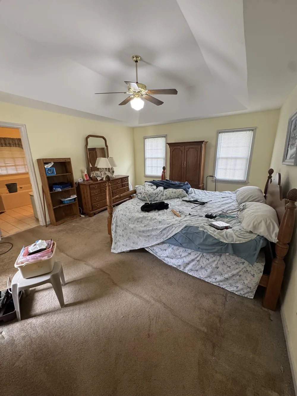 A furnished bedroom with a four-poster bed, dresser, armoire and bookshelf before an estate cleanout