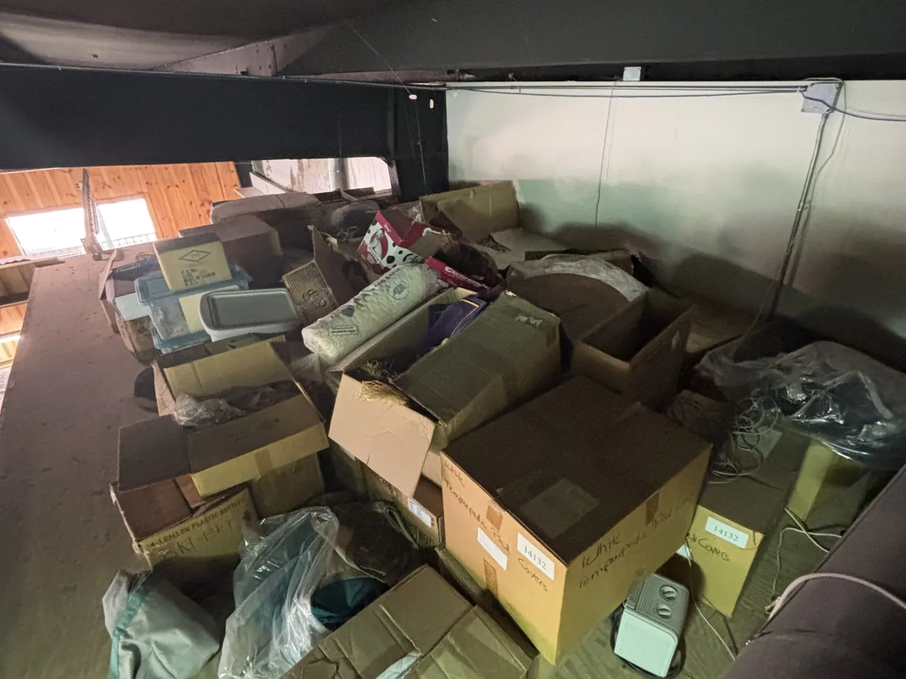 An attic space filled with cardboard boxes, storage bins and bags before a cleanout